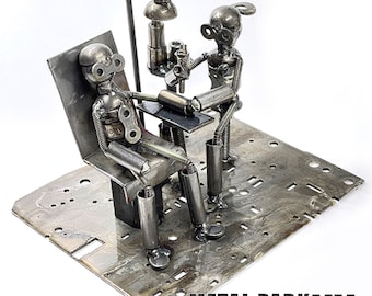 May include: A metal sculpture depicting a dentist and patient. The figures are crafted from recycled metal parts, with the dentist holding a tool over the patient. The sculpture is mounted on a rectangular metal base. The text "METAL PARK NY RECYCLED METAL ART" is visible.