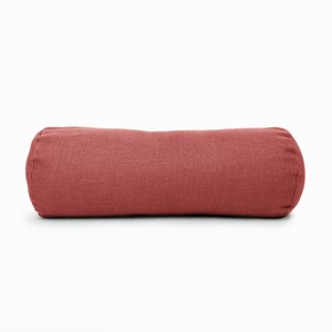 May include: A red cylindrical pillow made of a textured fabric.