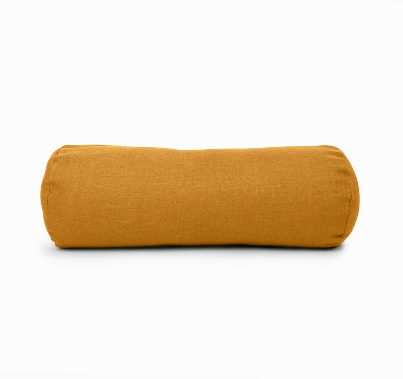 May include: A mustard yellow cylindrical pillow with a linen fabric cover.