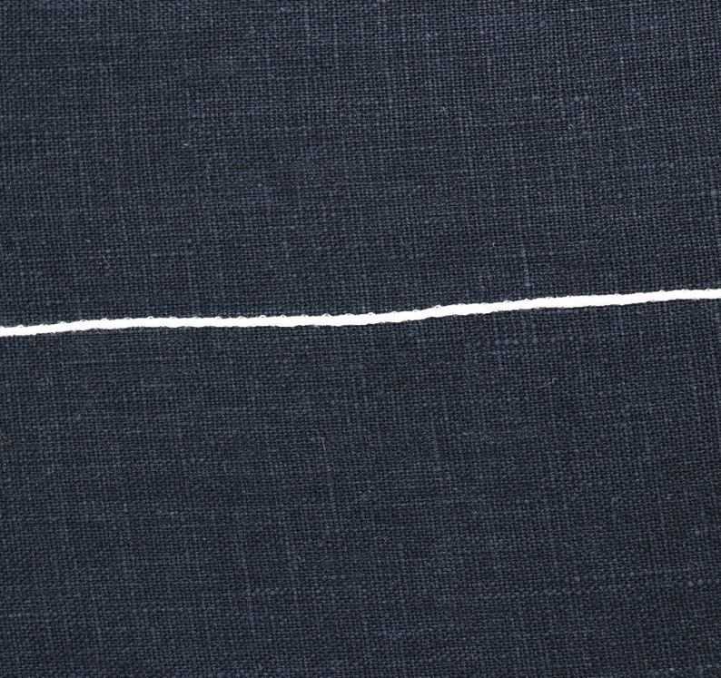 K&ouml;nnte beinhalten: Nahaufnahme eines dunkelblauen Stoffes mit einer einzigen wei&szlig;en Linie, die horizontal durch die Mitte verl&auml;uft.