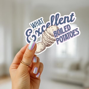 May include: A sticker with the text "What Excellent Boiled Potatoes" in a whimsical font. The sticker features an illustration of sliced potatoes. The sticker is held by a hand with iridescent nail polish and gold rings.