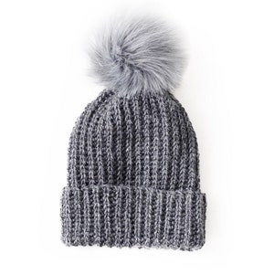 May include: A gray knitted beanie with a fluffy gray pom pom on top.