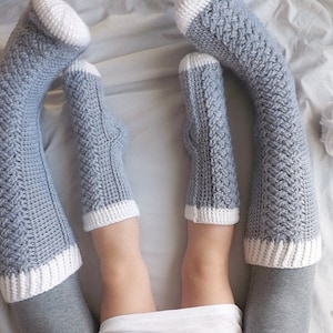 May include: A pair of gray and white crocheted knee-high socks with a braided pattern.