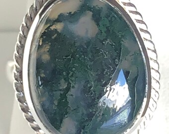 May include: A silver ring with a green and white moss agate stone set in a rope-like design.