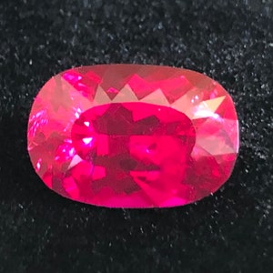 May include: A vibrant pink oval-shaped gemstone with a faceted cut.