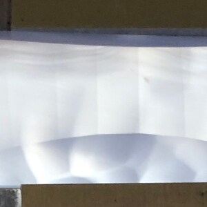 May include: A clear, rectangular, slightly curved glass prism.