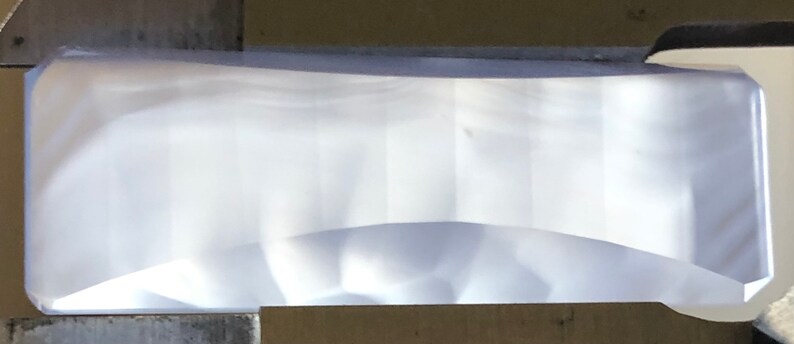 May include: A clear, rectangular, slightly curved glass prism.