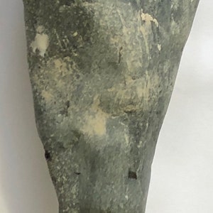May include: A smooth, grey, pear-shaped stone with white streaks and a pointed end.