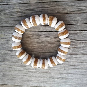 May include: A brown and white striped beaded bracelet. The beads are round and have a glossy finish.