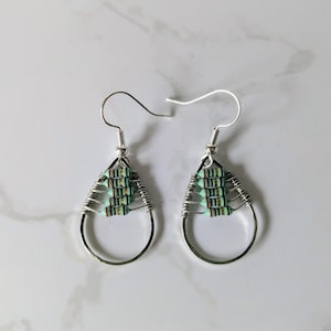May include: A pair of silver teardrop earrings with a cluster of green and brown resistors in the centre of each earring.