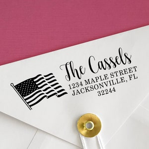 May include: A white envelope with a black and white American flag and the text "The Cassels 1234 Maple Street Jacksonville, FL 32244" printed on it.