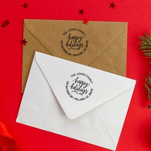 May include: Two white envelopes with a round, black, self-inking stamp that says "The Jones Family happy holidays 109 Bayside Dr | Willard, NC 28478". The envelopes are on a red background with gold stars.