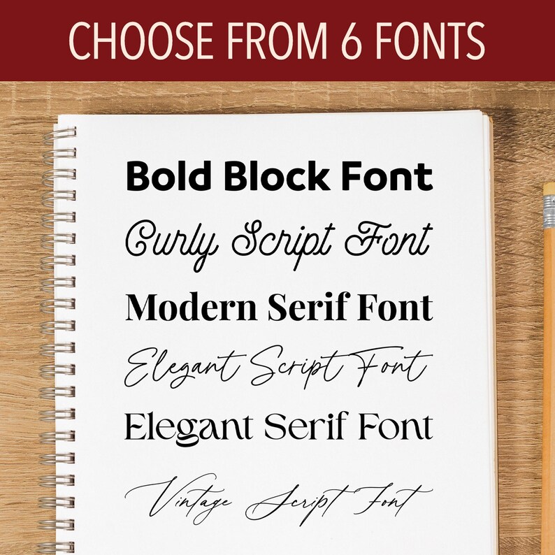May include: A spiral-bound notebook displays font options. The text "CHOOSE FROM 6 FONTS" is at the top. Below, six font styles are shown: Bold Block, Curly Script, Modern Serif, Elegant Script, Elegant Serif, and Vintage Script. A pencil rests on the right.