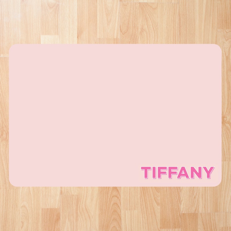 May include: A pink personalized desk mat with the name "TIFFANY" printed in pink.
