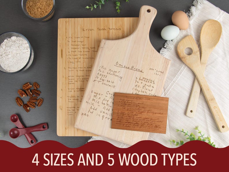 Three cutting boards are shown in different shapes, sizes, & wood grains. One is a medium wood color & is a large rectangle, one is a lighter-colored paddle, & the last is a dark-colored small rectangle. They're each engraved with a different recipe.