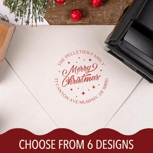 May include: A red ink stamp on a white envelope with the text "Merry Christmas" in a circular design. The stamp includes the family name and address. The image also shows a wooden stamp handle and the text "CHOOSE FROM 6 DESIGNS".
