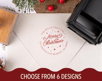 May include: A red ink stamp on a white envelope with the text "Merry Christmas" in a circular design. The stamp includes the family name and address. The image also shows a wooden stamp handle and the text "CHOOSE FROM 6 DESIGNS".