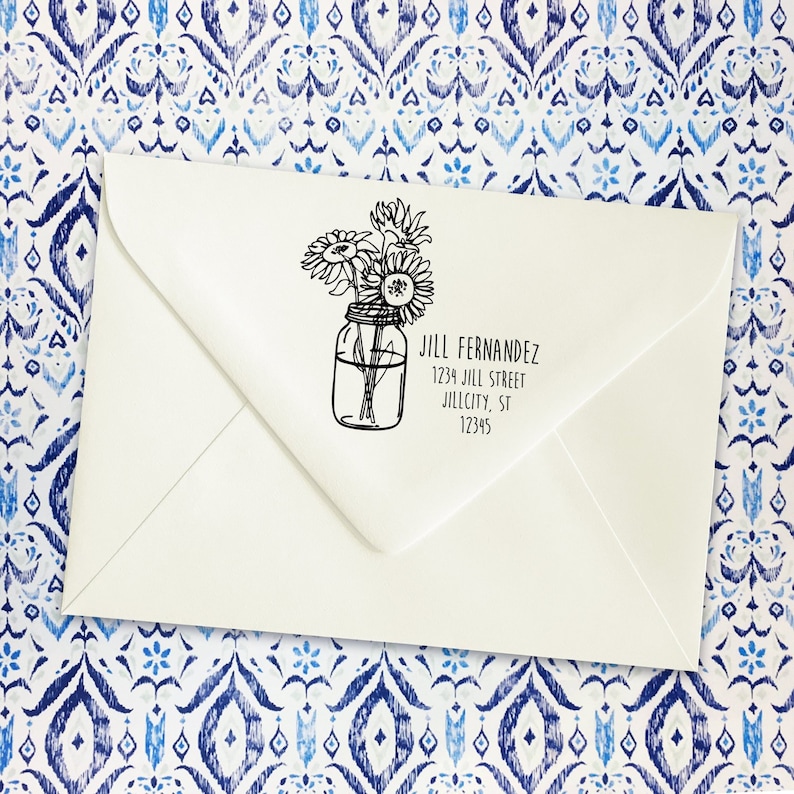 May include: A white envelope with a black and white return address label. The label features a drawing of sunflowers in a mason jar and the text "Jill Fernandez, 1234 Jill Street, Jillcity, ST 12345".