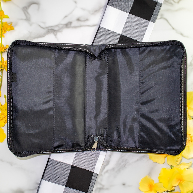 May include: Black zippered bible cover with a black and white checked pattern in the background.