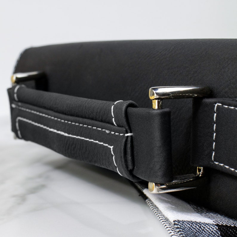 May include: Black leather carrying case with a white stitched handle and silver metal clasps.