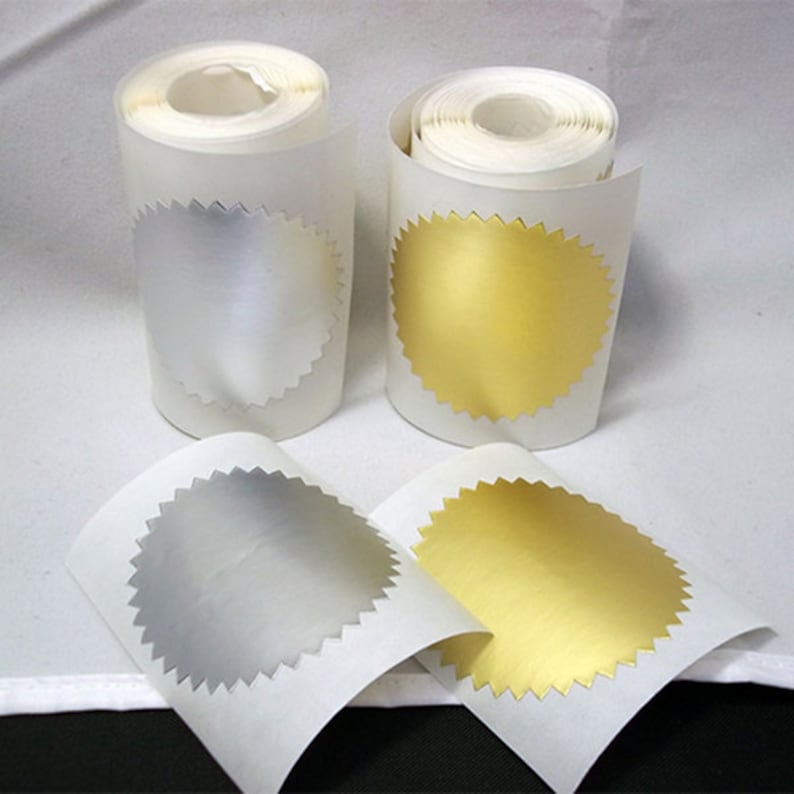 K&ouml;nnte beinhalten: Zwei Rollen Klebepapier, eine mit silbernen und eine mit goldenen runden Etiketten. Die Etiketten haben einen gewellten Rand.