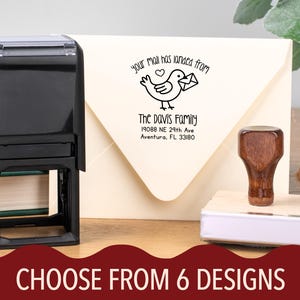 May include: A black self-inking stamp next to a wooden handled stamp. The stamp design features a bird carrying an envelope with the text "Your mail has landed from The Davis Family". The image also includes the text "CHOOSE FROM 6 DESIGNS".