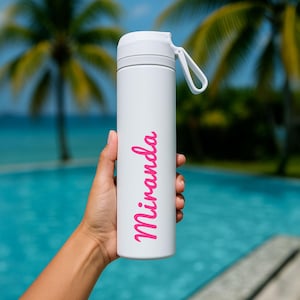 May include: A white insulated water bottle with the name "Miranda" in pink script. The bottle has a white lid and a white handle. The background shows a swimming pool and palm trees.