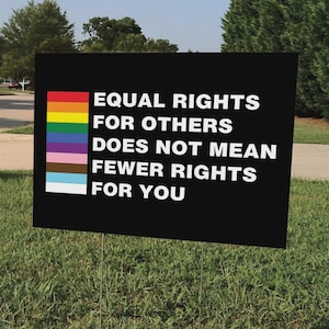 May include: A black sign with the text "EQUAL RIGHTS FOR OTHERS DOES NOT MEAN FEWER RIGHTS FOR YOU" in white. The sign has a rainbow-colored stripe on the left side.