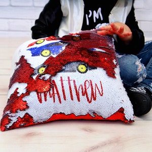 May include: A red and white reversible sequin pillow with a personalized name "Matthew" and a design of cartoon race cars.