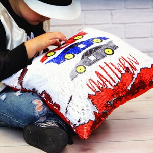 May include: A white and red reversible sequin pillow with a blue, red, and black car design and the name "Matthew" written in black.