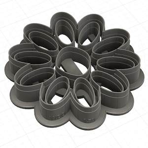 May include: A grey, multi-piece cookie cutter set in a floral design. The set is made of plastic and features a series of interconnected, petal-shaped cutters. The base of the cutter has the text "WDB" and "150".