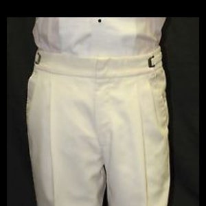 May include: White, knee-length, tailored pants with a pleat on each leg. The pants have a belt loop and a button closure.