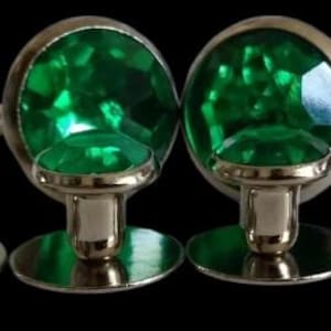 May include: Set of four green glass cufflinks and shirt studs. The cufflinks are round and have a silver base. The shirt studs are smaller and have a silver base with a green glass top.