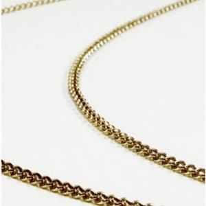 May include: A gold chain necklace with a delicate, twisted design. The chain is made of metal and has a shiny finish.