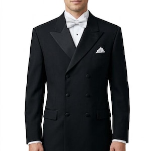 May include: A black double-breasted tuxedo jacket with satin peak lapels, worn over a white dress shirt with a black button stud. The ensemble includes a white patterned bow tie and a matching white pocket square tucked into the chest pocket.