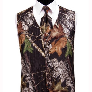 Puede incluir: Un chaleco de camuflaje marr&oacute;n, negro y verde con una corbata a juego. El chaleco tiene un cuello puntiagudo y un cierre de bot&oacute;n.