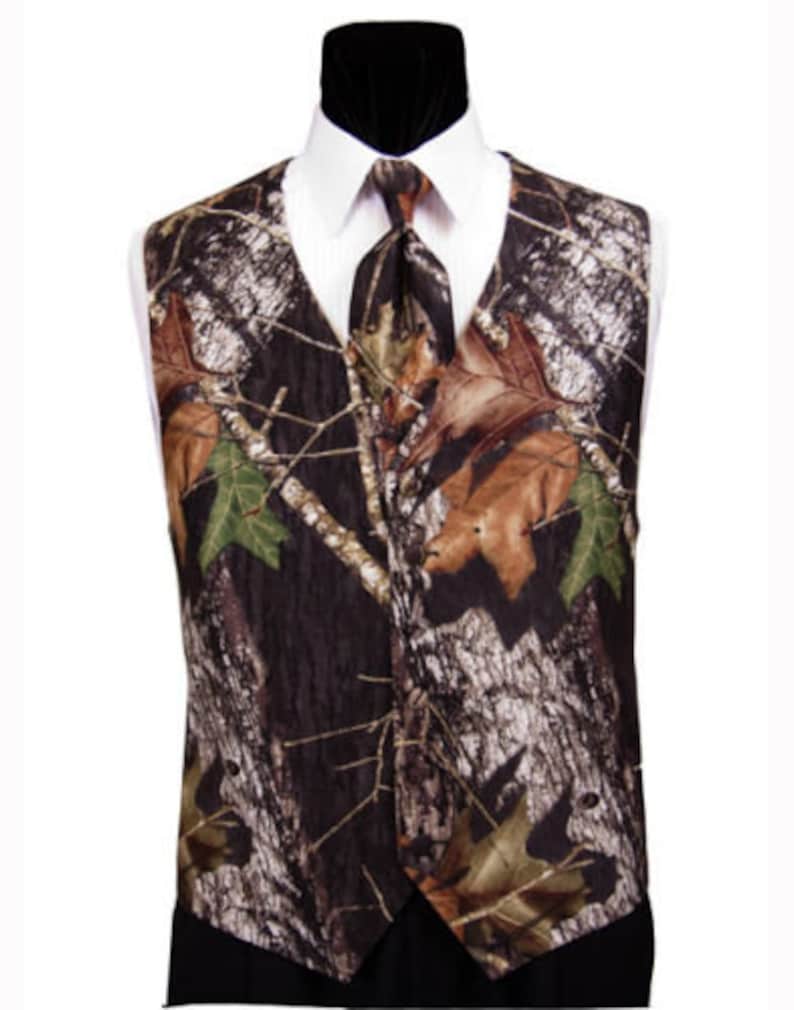 Puede incluir: Un chaleco de camuflaje marr&oacute;n, negro y verde con una corbata a juego. El chaleco tiene un cuello puntiagudo y un cierre de bot&oacute;n.