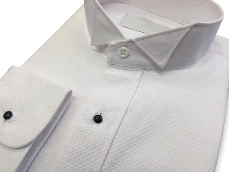 May include: A white dress shirt with a button-down collar and a textured fabric. The shirt has a single button on the front and two buttons on the cuffs.
