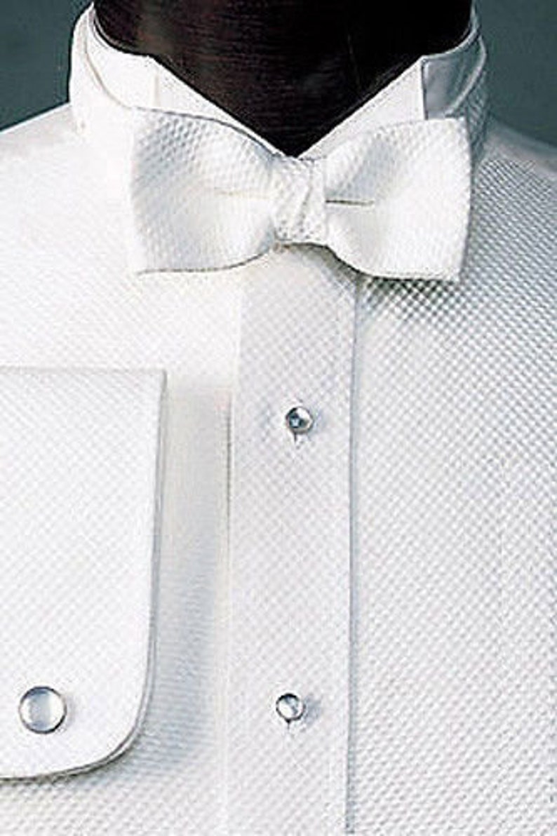 May include: A white dress shirt with a white bow tie and a wing collar. The shirt has a textured pattern and two silver buttons.