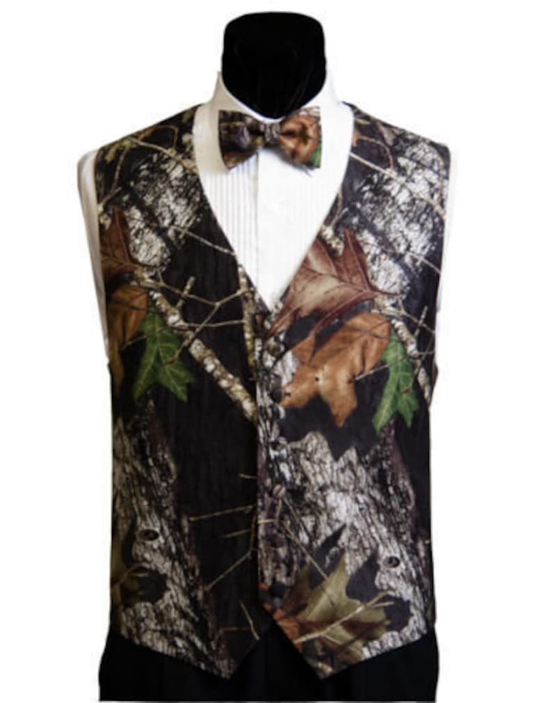 May include: A black waistcoat with a camouflage pattern in shades of brown, green, and white. The waistcoat has a button closure and a bow tie.