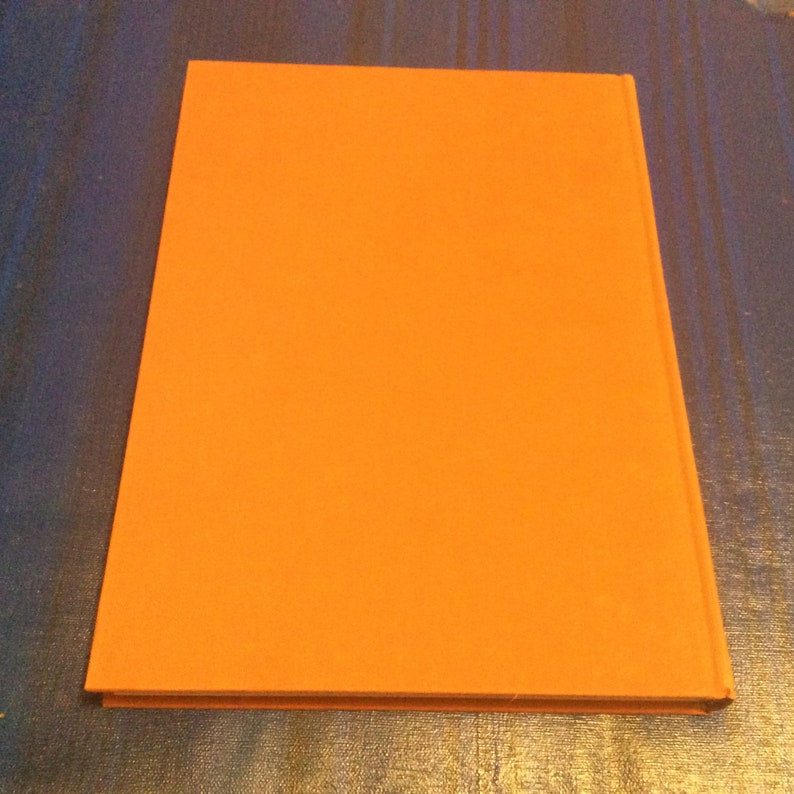 May include: A solid orange hardcover book with a plain cover.