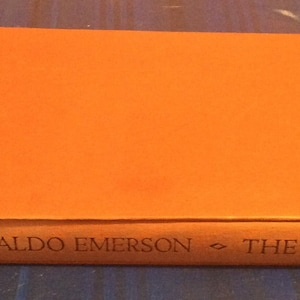 May include: An orange hardback book with the title "RALPH WALDO EMERSON - THE ESSAYS" printed on the spine.