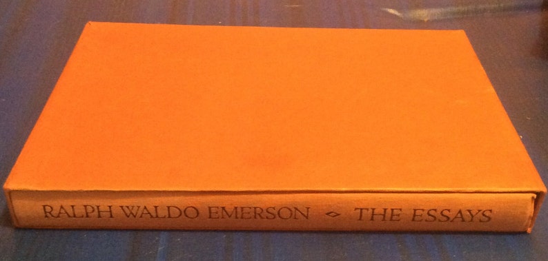 May include: An orange hardback book with the title "RALPH WALDO EMERSON - THE ESSAYS" printed on the spine.