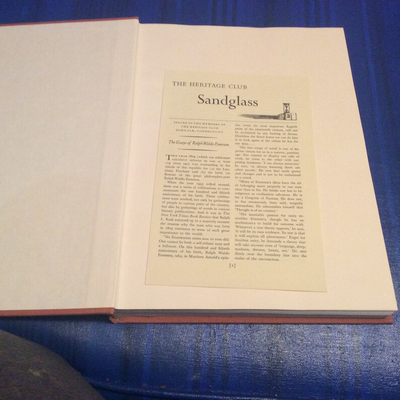 May include: A close-up of a book cover with the title "Sandglass" and the text "The Essays of Ralph Waldo Emerson". The book is part of "The Heritage Club" series.
