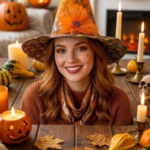 May include: A pointed witch hat featuring an orange and brown autumn-themed pattern with a large orange fabric flower at the base. The hat has a wide brim with a dark, intricate leaf print and is worn by a person with long auburn hair and a scarf.