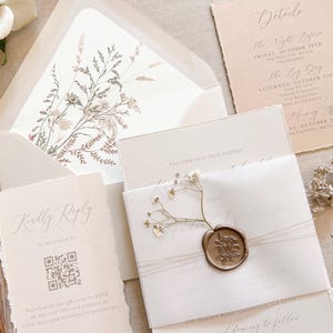 May include: Elegant wedding stationery set featuring a cream-colored invitation with a wax seal and floral accents. Includes a reply card with a QR code, details card, and an envelope with a botanical design.