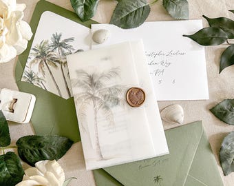 Op de afbeelding: Een trouwkaartenset met saliegroene enveloppen, een doorschijnende pergamijn omslag met een palmboomillustratie en een ronde bronzen waszegel. De set bevat een witte kaart met palmboomkunst en een witte envelop met zwarte kalligrafie.