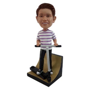 May include: A bobblehead figurine of a person on a scooter. The figurine wears a striped purple and white shirt, black pants, and black and white sneakers. The scooter is silver and black, and the base is a ramp.