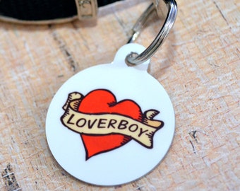May include: White round dog tag with a red heart and a banner that says "Loverboy" in a vintage tattoo style.