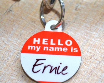 May include: Red and white dog tag with the text "HELLO my name is Ernie" in black.
